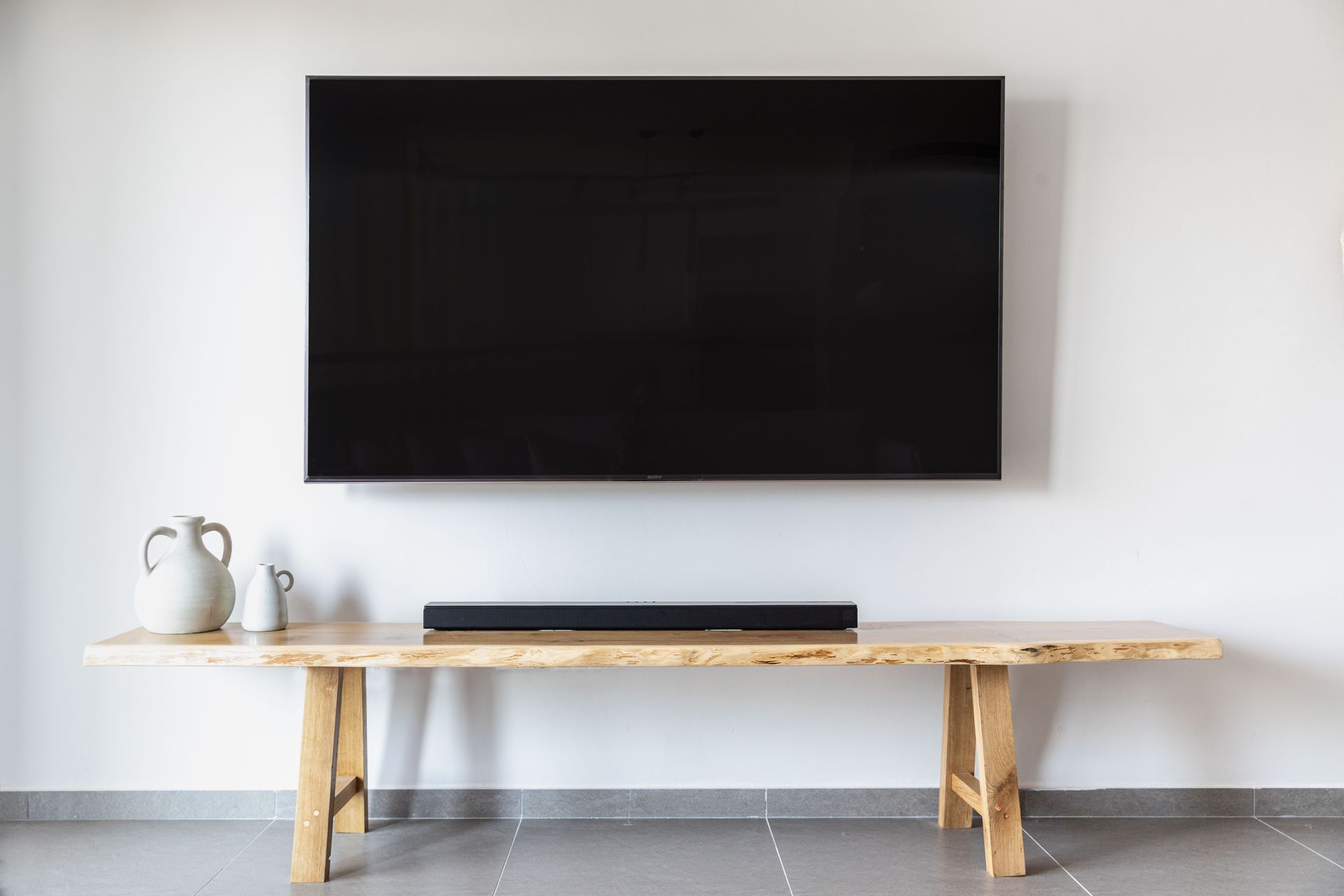 Flat screen TV mounted on wall over a wooden console in a living room