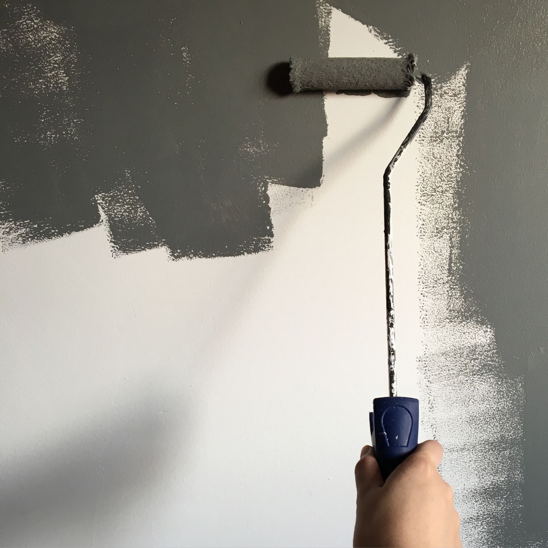 Person painting an interior wall with a roller